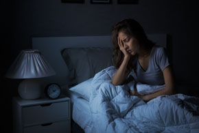 Depressed young Asian woman sitting in bed cannot sleep from insomnia